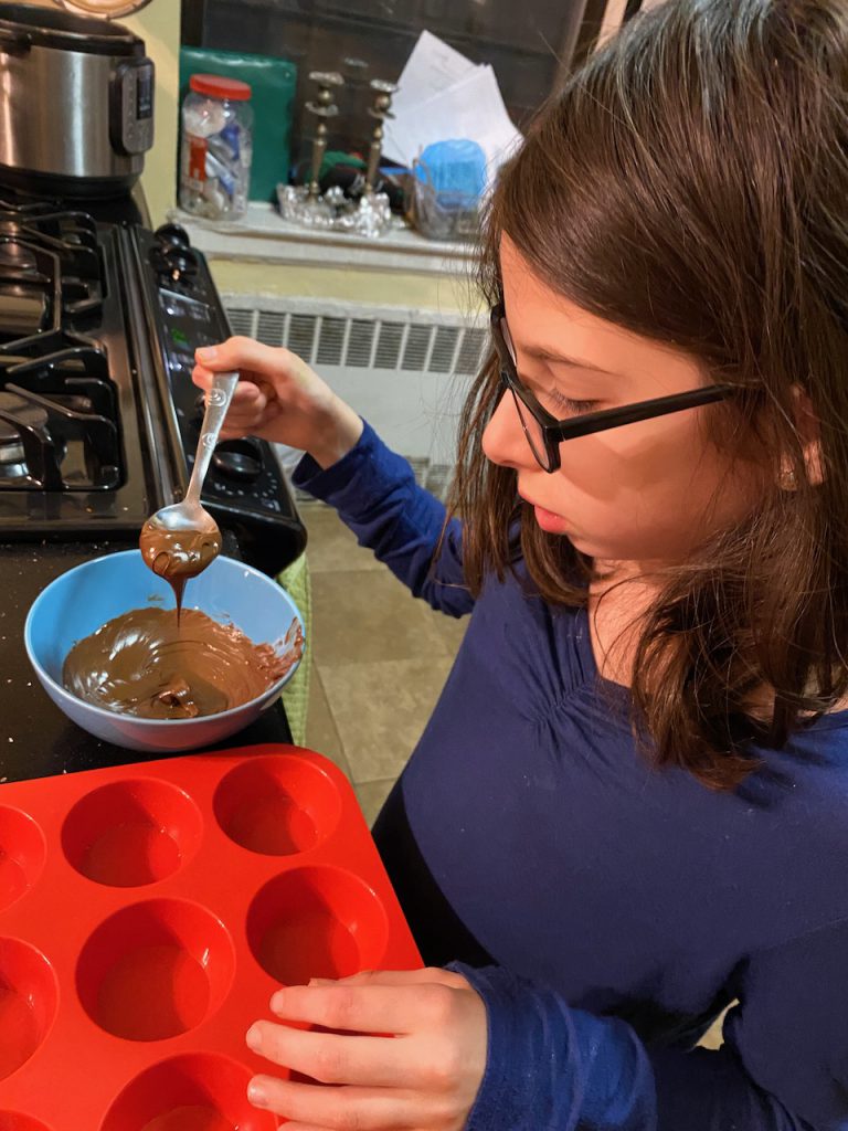 Girl adding chocolate to muffin pan